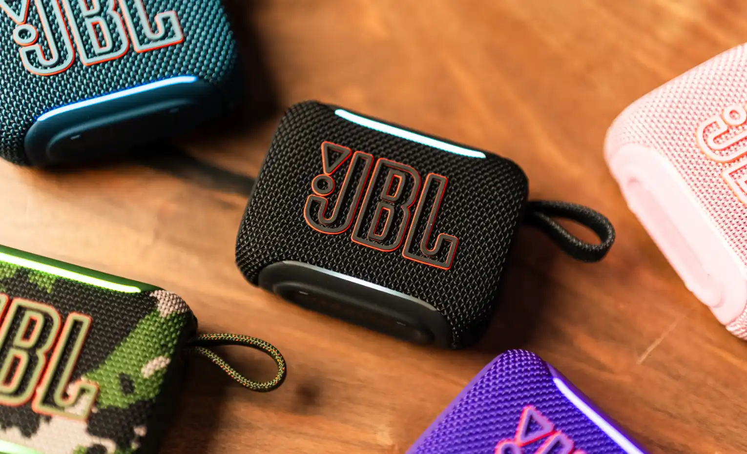 راهنمای خرید اسپیکر USB-C و بلوتوث (مهر 1405) اسپیکر کوچک مشکی JBL Go میان چند رنگ دیگر روی میز