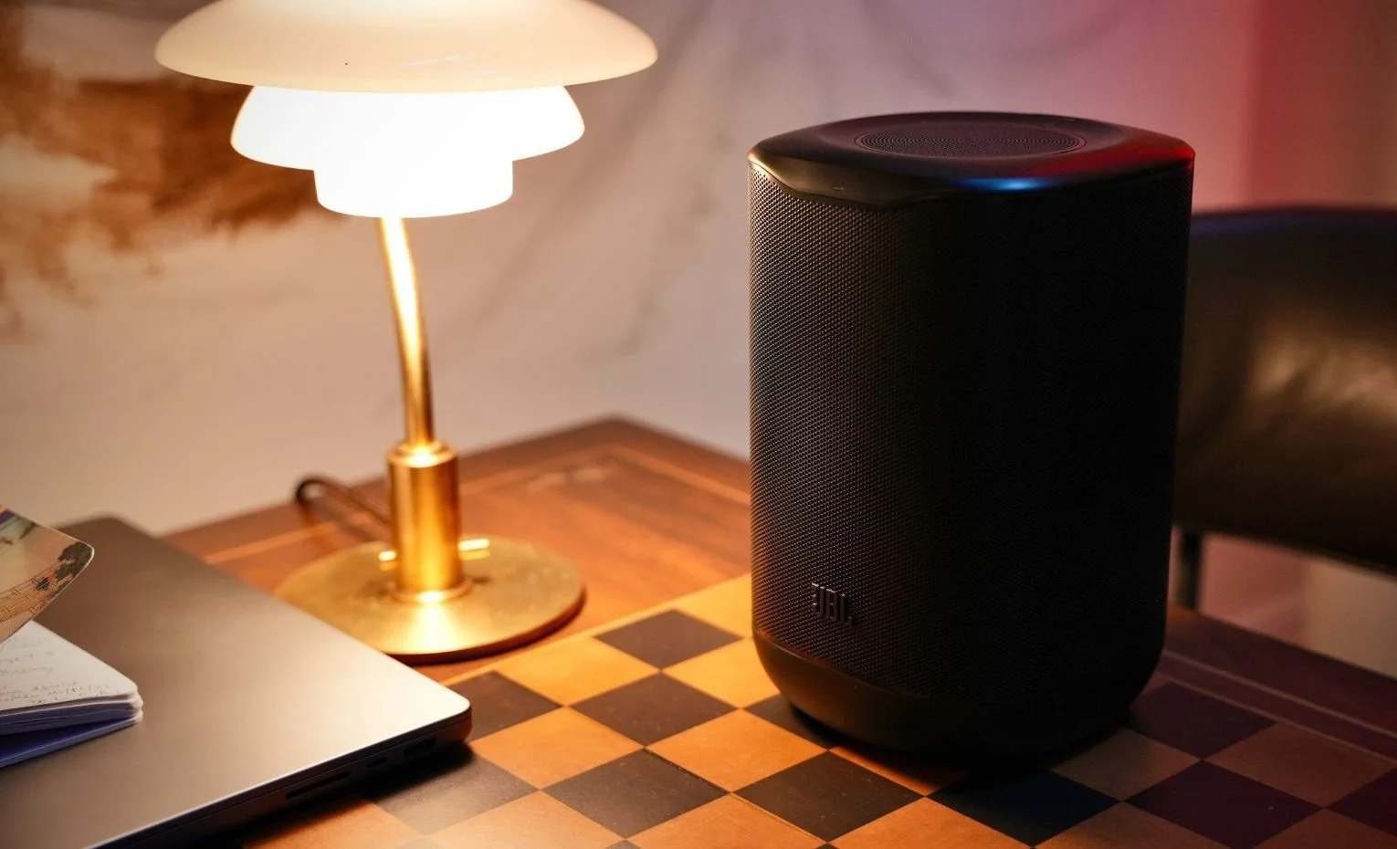 اسپیکر جی بی ال Cove M1؛ بررسی امکانات و کیفیت صدا اسپیکر JBL Cove M1 کنار چراغ رومیزی و لپتاپ