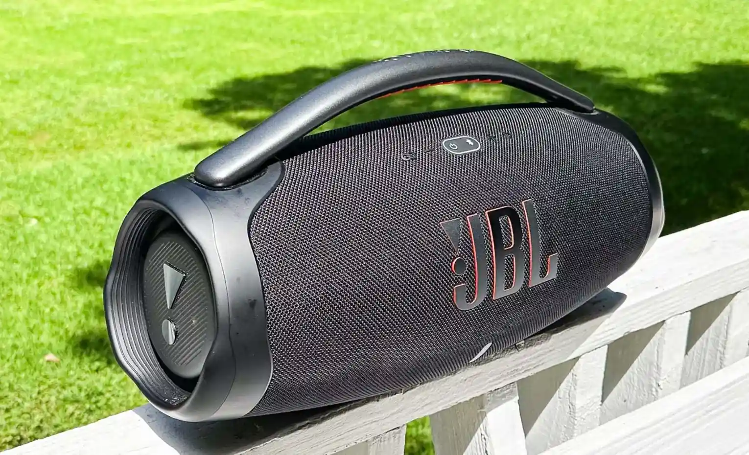 یک اسپیکر بزرگ یا دو کوچک، کدام را بخریم؟ (مهر 1405) اسپیکر JBL Boombox 3 با دسته روی نرده در فضای سبز
