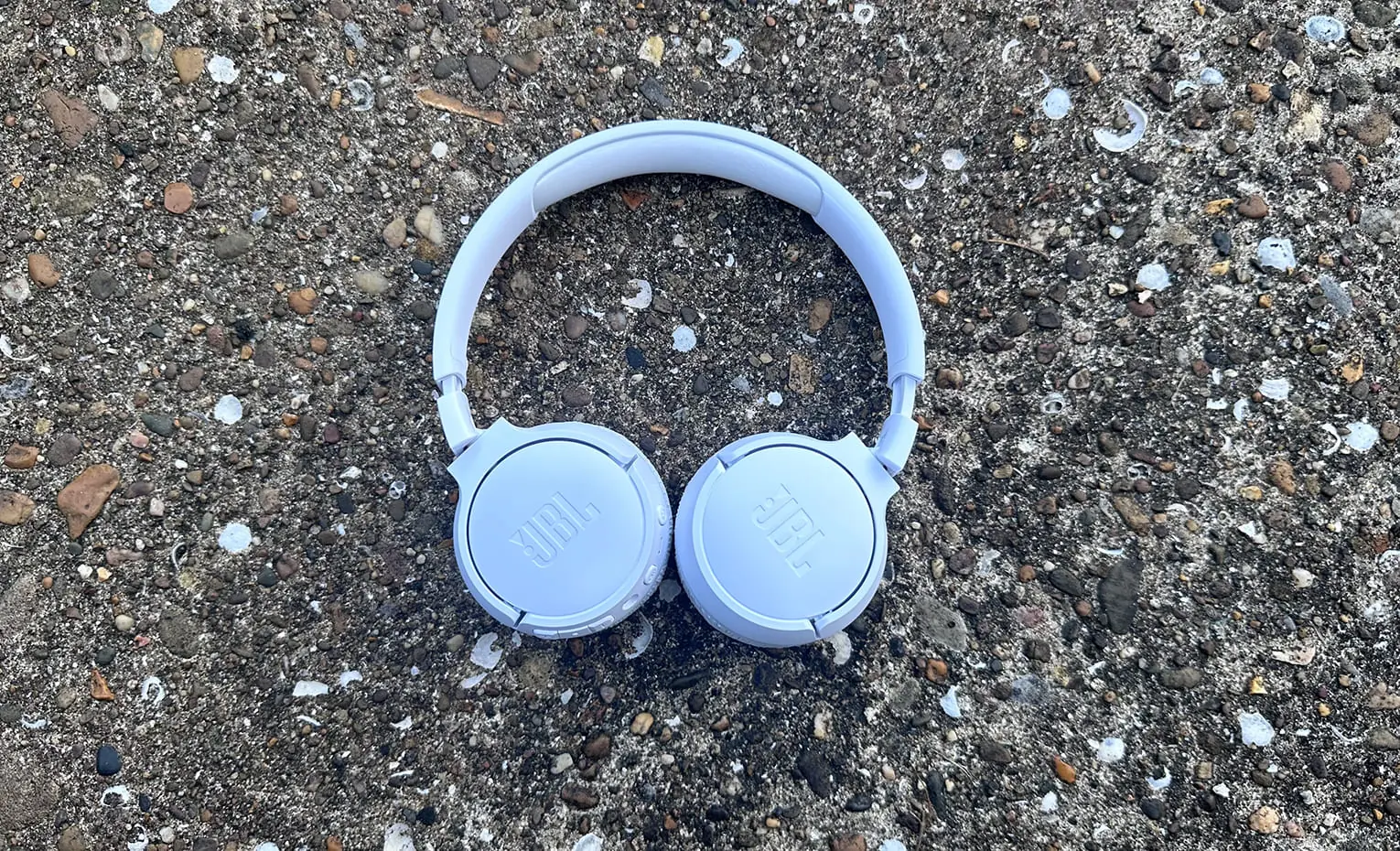 راهنمای خرید هدفون نویز کنسلینگ شهریور 1403 هدفون آبی JBL Tune 670NC روی سطح سنگی